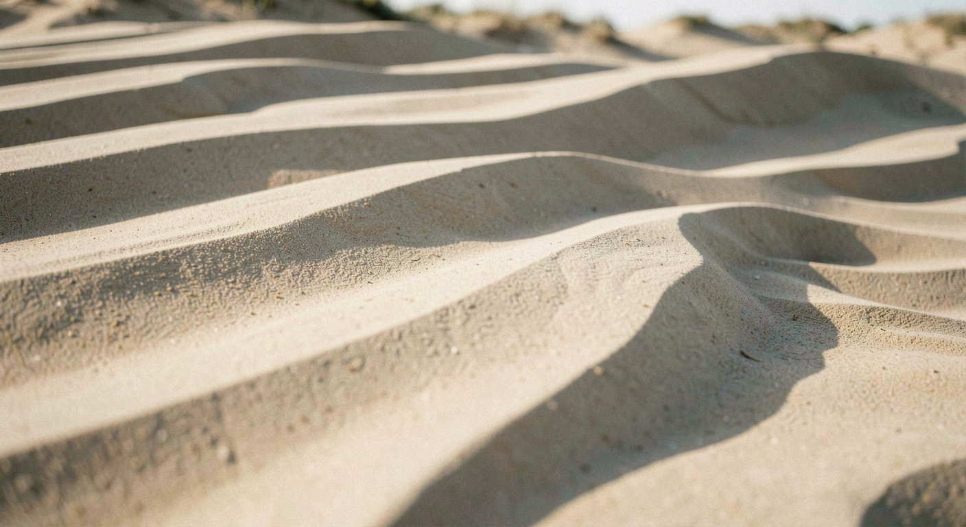Crêtes de dunes superposées vues au téléobjectif, alternance de bandes claires et d'ombres sans ciel visible